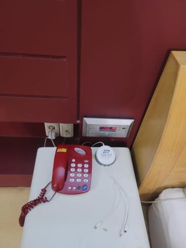 un teléfono rojo sentado en la parte superior de una cama en B Hotel, en Cheonan