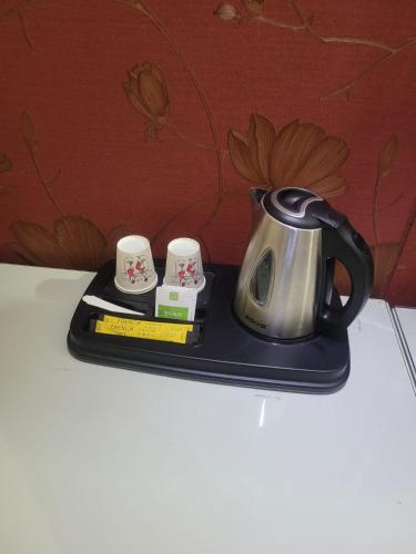 a tea kettle and two cups on a tray at B Hotel in Cheonan