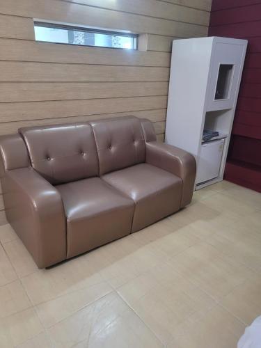 un sofá de cuero marrón en una habitación con nevera en B Hotel, en Cheonan