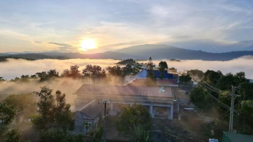Blick auf eine neblige Stadt mit der Sonne im Hintergrund in der Unterkunft Hồng Ngọc 1 Hotel Tà Đùng in Biđong
