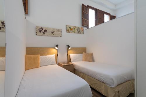 Duas camas num quarto com paredes brancas e janelas em Car-Loft next to Arucas Cathedral em Arucas