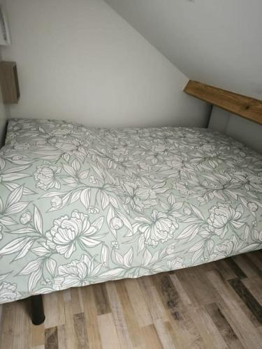 Bett in einem Zimmer mit einer Bettdecke mit Blumen in der Unterkunft Petite dépendance privée 