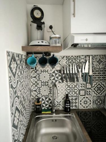 eine Küche mit einem Waschbecken und einer Uhr an der Wand in der Unterkunft Petite dépendance privée 