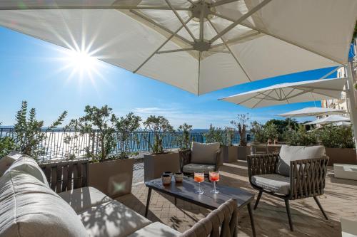 a patio with a table and chairs and an umbrella at Palazzo Alfeo Aparthotel in Siracusa