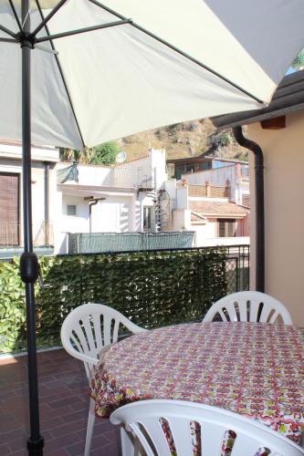 einen Tisch und Stühle mit Sonnenschirm auf dem Balkon in der Unterkunft Donna Lucia in Giardini-Naxos