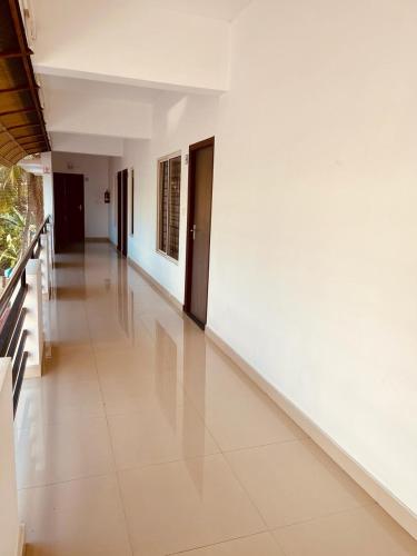 an empty hallway with white walls and white tile floors at Amalas Lodge in Trivandrum