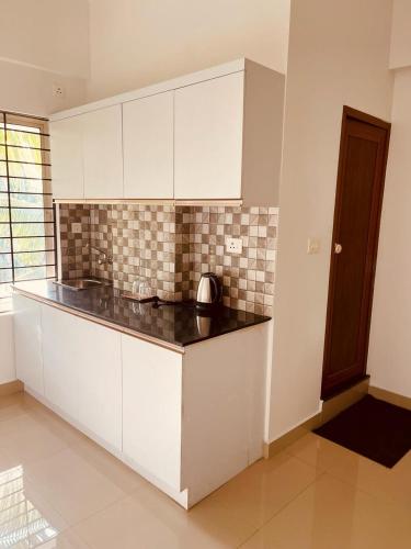 a kitchen with white cabinets and a black counter top at Amalas Lodge in Trivandrum