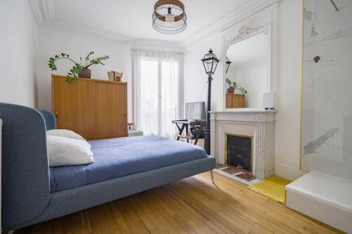 een slaapkamer met een blauwe bank en een open haard bij Magnifique appartement Lumineux in Saint-Mandé