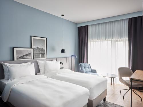 una habitación de hotel con 2 camas y una silla en Radisson Hotel Graz en Graz