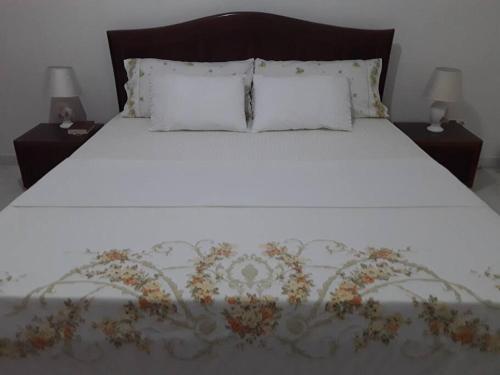 un letto bianco con due comodini e due cuscini sopra di Kaza Mamai di Fora, o conforto da sua estadia a Calheta