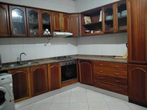 una cucina con armadi in legno, lavandino e lavastoviglie di Kaza Mamai di Fora, o conforto da sua estadia a Calheta