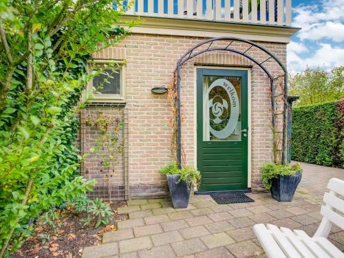 une porte verte sur une maison en briques avec un banc blanc dans l'établissement Homely Apartment in Noordwolde with Balcony, à Noordwolde