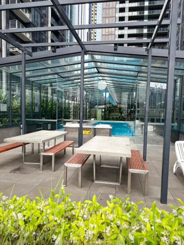 two tables and benches in a building with a pool at The Southbank Central Retreat in Melbourne