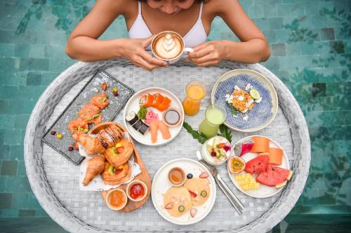 a woman sitting at a table with a cup of coffee at Anantara Vacation Club Mai Khao Phuket in Mai Khao Beach