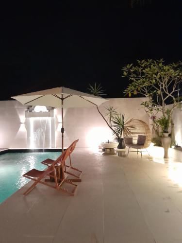 a pool with a chair and an umbrella next to a pool at Villa Padi Pakem in Pakem