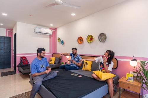 three people sitting on a bed in a room at The Hosteller Jaipur, MI Road in Jaipur