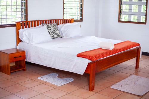 Schlafzimmer mit einem Bett mit einem Holzrahmen und einem Tisch in der Unterkunft EAZY BREEZY BACKPACKERS in Daressalam