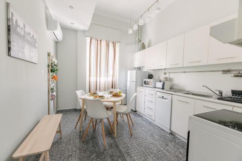 a kitchen with white cabinets and a table and chairs at Ourania by Heloni Apartments in Athens