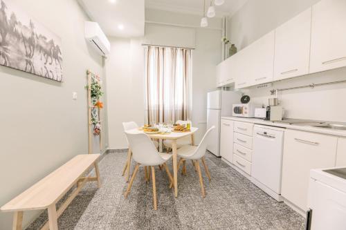 a kitchen with white cabinets and a table and chairs at Ourania by Heloni Apartments in Athens