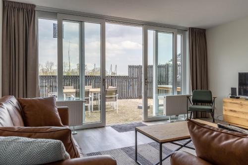 a living room with sliding glass doors with a view at Welcome in - Appartement - Paviljoenwei 4 - Sneek 'Havenzicht' in Offingawier