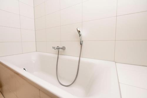 a shower in a white tiled bathroom with a tub at Welcome in - Appartement - Paviljoenwei 4 - Sneek 'Havenzicht' in Offingawier