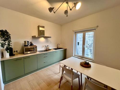 una cucina con armadi verdi e un tavolo con sedie di Duplex chic et spacieux - Hypercentre a Liegi
