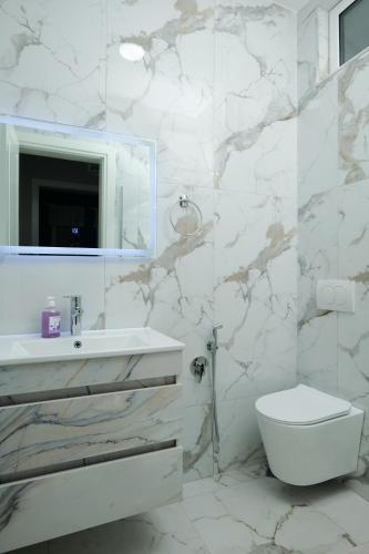 a white bathroom with a sink and a toilet at Travelers' Korça Home in Korçë