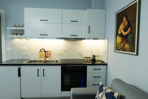una cocina con armarios blancos y fregadero en Travelers' Korça Home, en Korçë