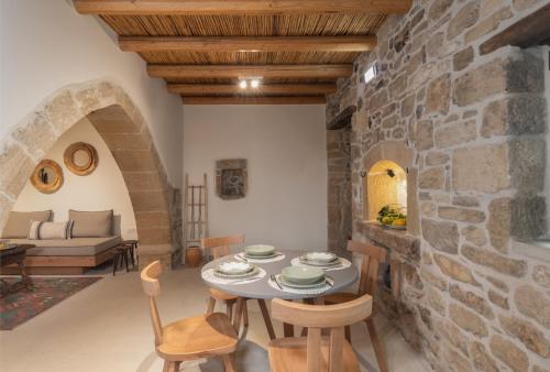 a room with a table and chairs and a stone wall at St-Ten Stone Built Village in Áyioi Dhéka