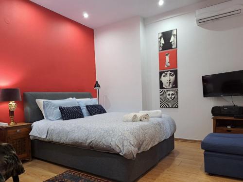 a bedroom with a bed and a red wall at GRAND BLUE SUITE DI GIORGIO 10min from Piraeus port in Piraeus