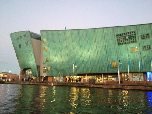 a large green building next to a body of water at Botel Sailing Home in Amsterdam