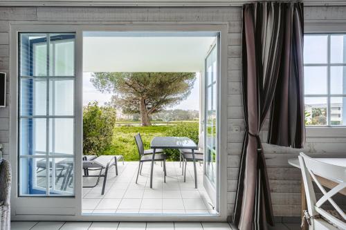 Une porte ouverte s'ouvre sur une terrasse avec une table et des chaises. dans l'établissement Vue et face Golf Port Bourgenay, à Saint-Hilaire-de-Talmont