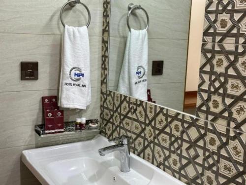 a bathroom with a sink and a mirror at Pearl Inn Hotel in Karachi