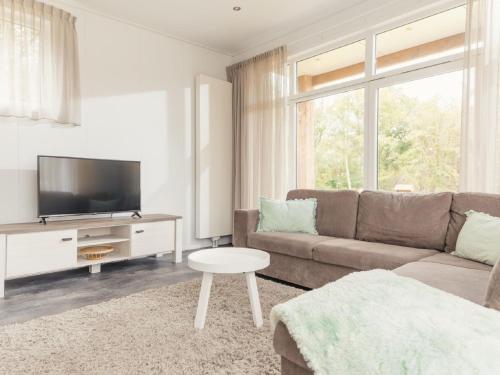 a living room with a couch and a tv at Cozy chalet with garden at the edge of the forest in Rijssen