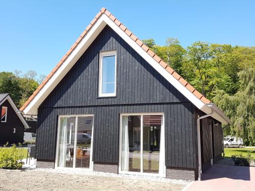 uma casa preta com um telhado de gambrel em Cozy house with a dishwasher in the middle of the Achterhoek em Almen