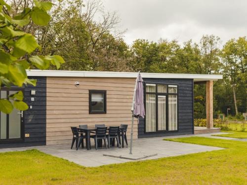 een klein huis met een tafel en stoelen op een patio bij Cozy chalet with garden at the edge of the forest in Rijssen