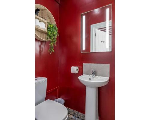 a red bathroom with a toilet and a sink at The Wellesley in Belfast