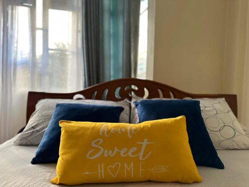 un letto con cuscini blu e un cuscino giallo di Amani Stays a Embu
