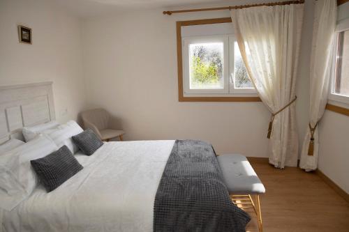 a bedroom with a white bed and two windows at Casa Larán in Chantada