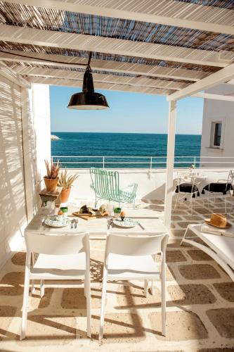 un patio con tavoli e sedie bianchi e l'oceano di Casa Solomare by Momò Apulia a Monopoli