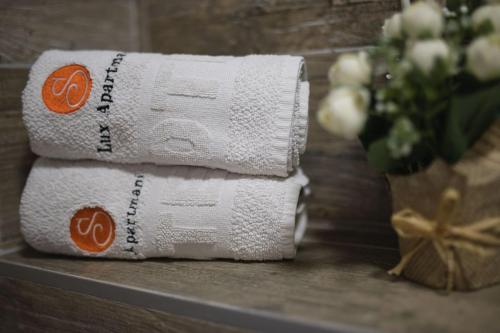 a stack of towels on a table with a vase of flowers at Guest House S-Lux in Petrovac na Moru