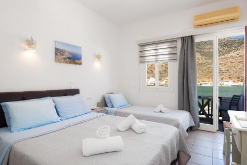 two beds in a room with a view of the ocean at Simeon Rooms & Apartments in Kamares