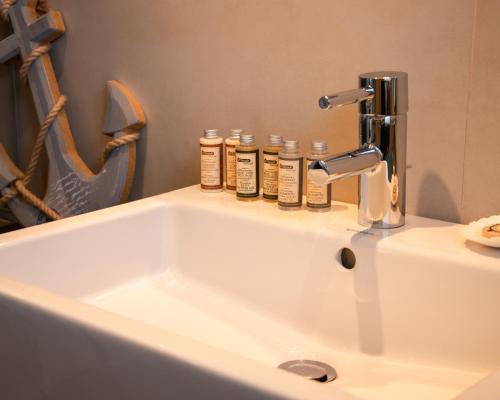 - un lavabo dans la salle de bains avec 4 bouteilles d'odorisants dans l'établissement Ferien-Lodge Lindau - Private Sauna & nah am See, à Lindau