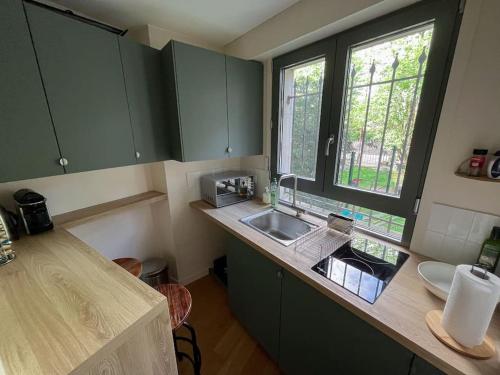 eine kleine Küche mit einem Waschbecken und einem Fenster in der Unterkunft Studio agréable & charmant + WI-FI in Neuilly-sur-Seine