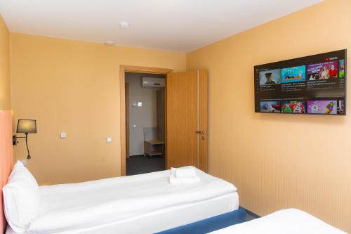 a room with two beds and a tv on the wall at Отель KOKSHETAU in Kokshetau