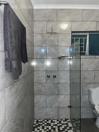 a bathroom with a shower with a glass door at @Eland B&B in Mokopane