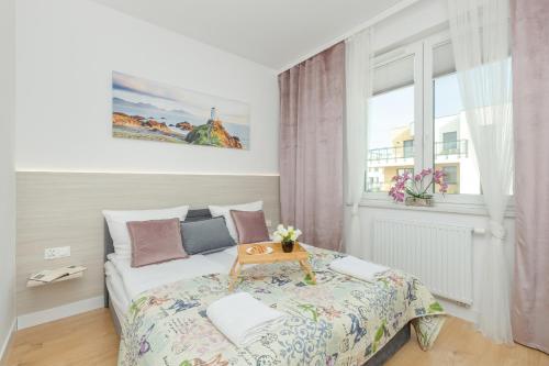 Un dormitorio con una cama con una mesa encima. en Nowy Świat Stylish, Seaside Apartment with Balcony & Parking Puck by Noclegi Renters, en Puck