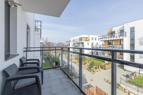 Cet appartement dispose d'un balcon avec des chaises et une vue sur la cour. dans l'établissement Nowy Świat Stylish, Seaside Apartment with Balcony & Parking Puck by Renters, à Puck