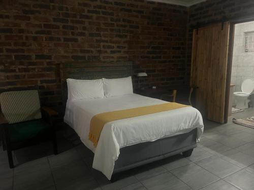a bedroom with a bed and a brick wall at @Eland B&B in Mokopane