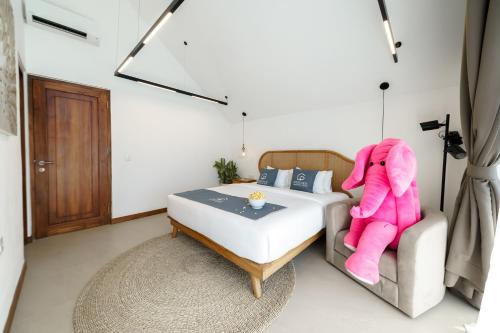 Un dormitorio con una cama con un elefante rosa sentado en un sofá en Premier Umalas Villas en Kerobokan